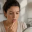 Femme touchant sa bouche, symbolisant la sensation de brûlure de la glossodynie